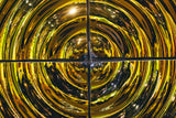 Close-up of a gold-finished modular glass wall panel 'Interference X4' with a circular ripple effect, reflecting an exhibition space with bright lights.