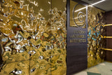 Luxury Designer Wall Panels – Aqua High Wave gold glass panels in an interior setting, featuring a reflective, undulating surface with a luxurious aesthetic.