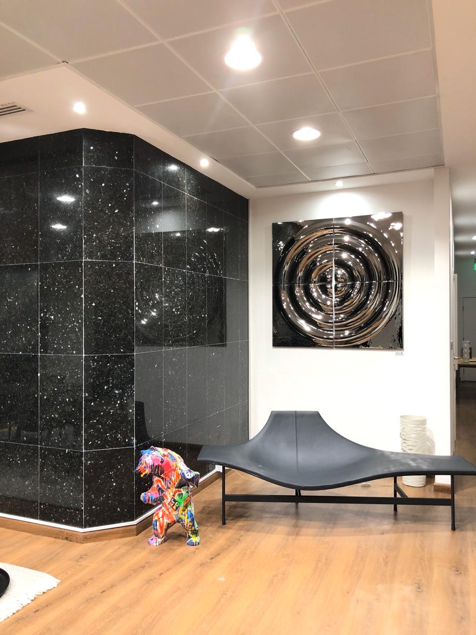 Reflective modular silver glass wall panels  with circular patterns in a modern interior near a staircase with black railing