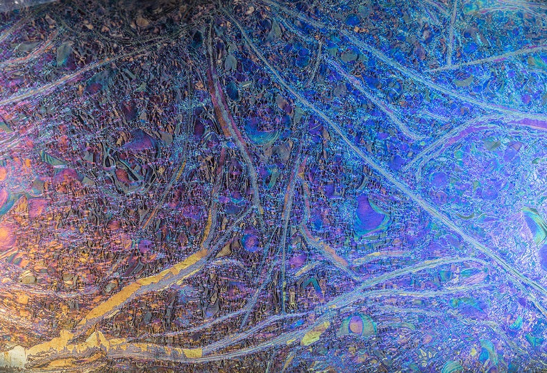 Luxurious chameleon glass wall panel with intricate textures and iridescent hues, reflecting a blend of blue, purple, and gold tones. A modern and artistic decorative glass panel ideal for upscale interiors