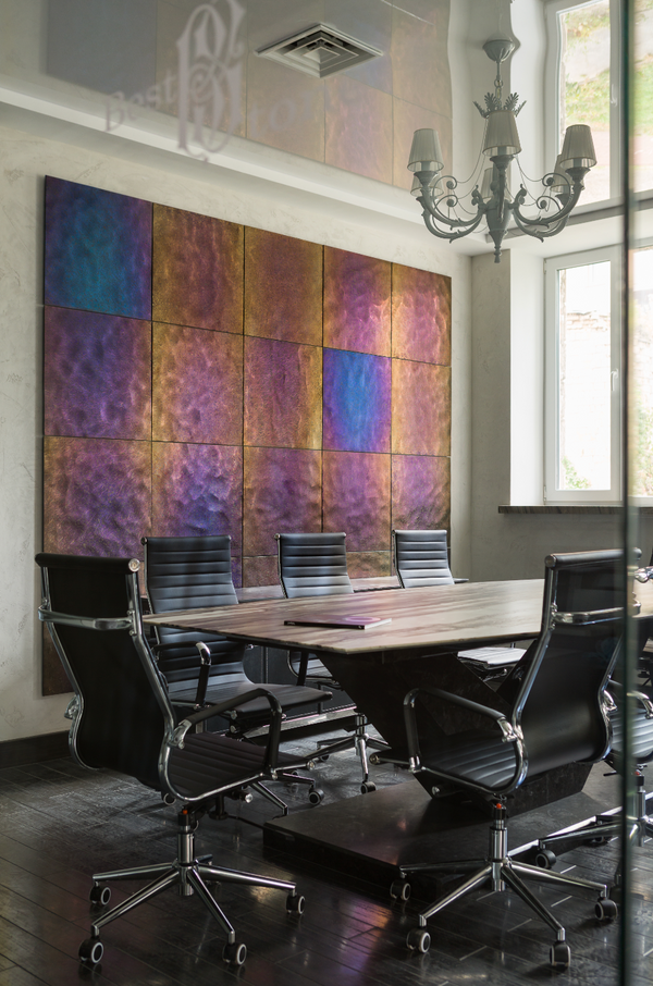 Luxury interior featuring chameleon glass wall panels with an iridescent metallic finish in shades of gold, bronze, and purple. A sophisticated meeting room design with modern furniture and elegant decor.