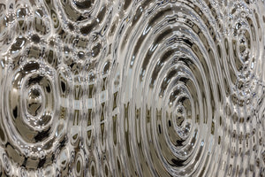 Close-up view of a silver glass panel showcasing detailed ripples and reflections, perfect for modern decor applications.