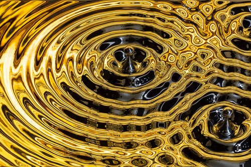 A decorative bathroom towel rack featuring a mesmerizing ripple design in gold and silver tones.