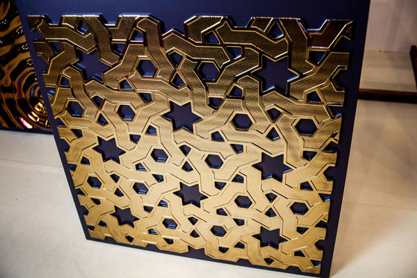 A decorative glass wall panel featuring an intricate golden Eastern geometric pattern with interlocking stars and hexagons on a dark background