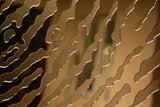 Close-up of fingerprint-inspired glass texture with a reflective gold finish.