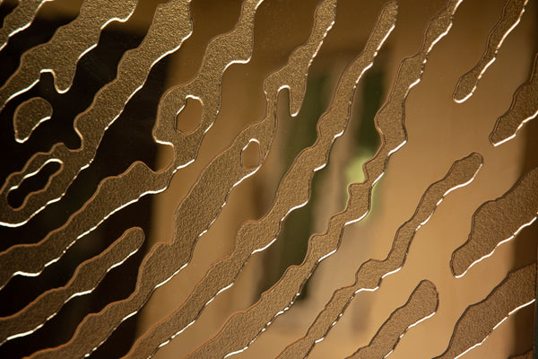 Close-up of fingerprint-inspired glass texture with a reflective gold finish.