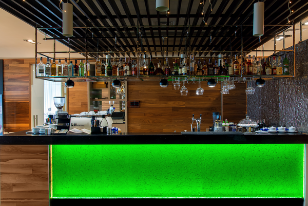 Flora green wall interior panel serves as a glowing green front panel for a modern bar, adding a luxurious ambiance with its textured surface.