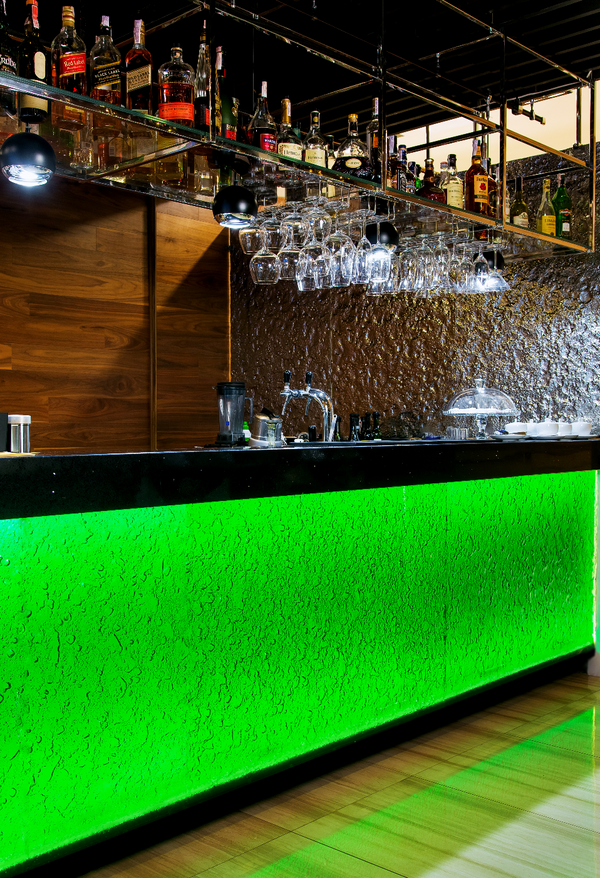 Illuminated Flora wall panel stands as a statement piece in a contemporary bar, bringing depth and vibrancy to the space
