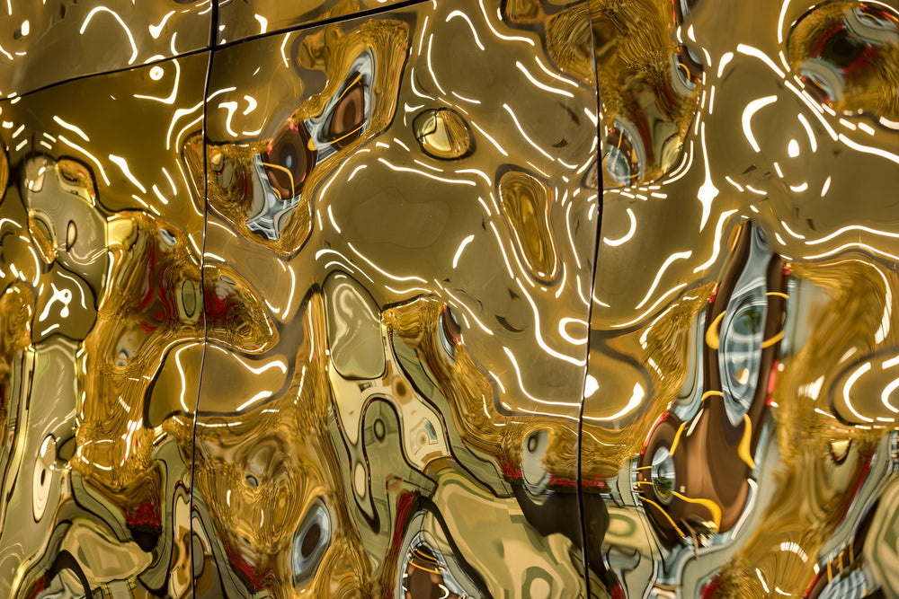 Luxury wall panels – Close-up of the luxury glass wall panel "Aqua High Wave" in a gold finish, with light reflecting off the panels
