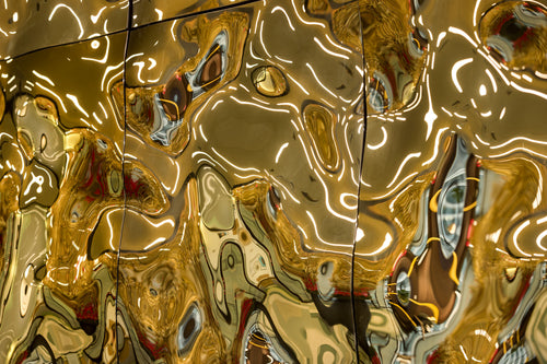 Luxury wall panels – Close-up of the luxury glass wall panel "Aqua High Wave" in a gold finish, with light reflecting off the panels