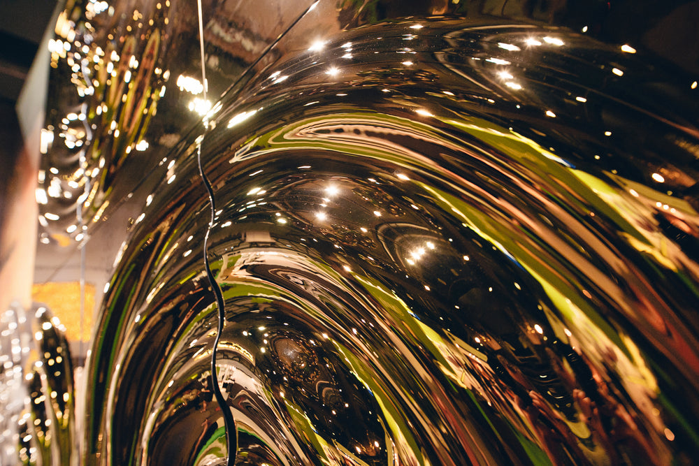 Gold-finished modular glass wall panel "Interference x4" with a circular ripple design, mounted above a vinyl player in a modern interior