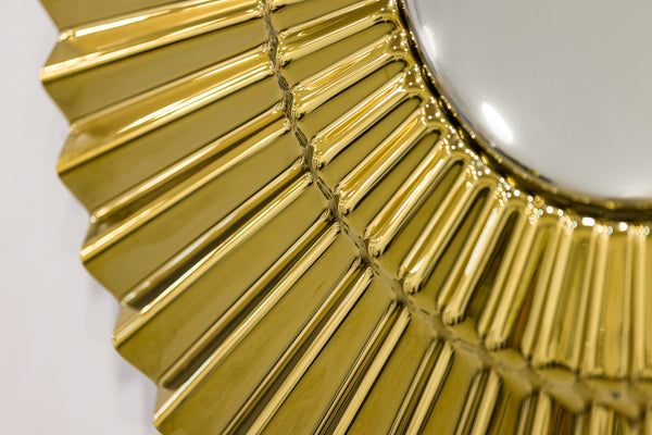 Close-up of golden sunburst wall decor showing intricate glass details.