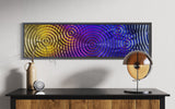 Interference 5 Drops Mural, a modern glass wall art piece with a dynamic ripple pattern in vibrant gold, purple, and blue hues.