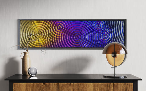 Interference 5 Drops Mural, a modern glass wall art piece with a dynamic ripple pattern in vibrant gold, purple, and blue hues.
