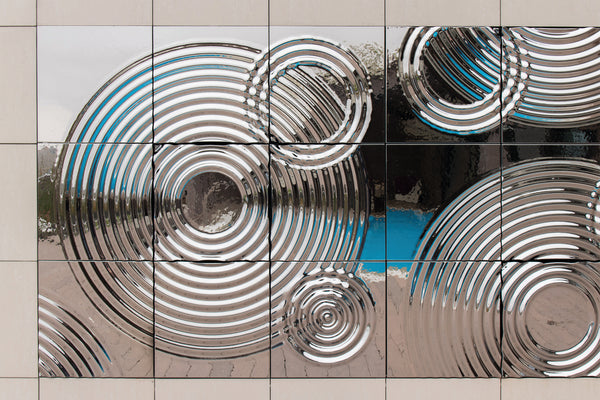 Interference exterior glass wall panel with concentric circular relief and reflective chrome finish