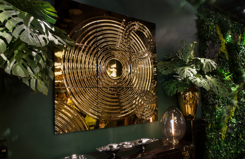 Illuminated golden Interference glass panel mounted in a dark, tropical-inspired space.
