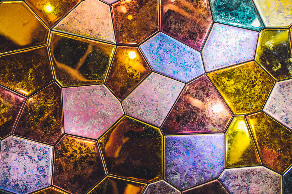 Iridescent glass mosaic wall art with a blend of gold, blue, and bronze hues, creating a mesmerizing decorative accent.