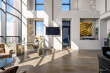 Luxury modern interior with gold circular glass panel, glass desk, high ceilings and natural light-filled space.