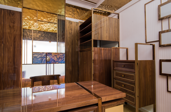 Luxury interior featuring gold glass panels, rich wooden furniture, and decorative partitions with intricate glass and metal detailing