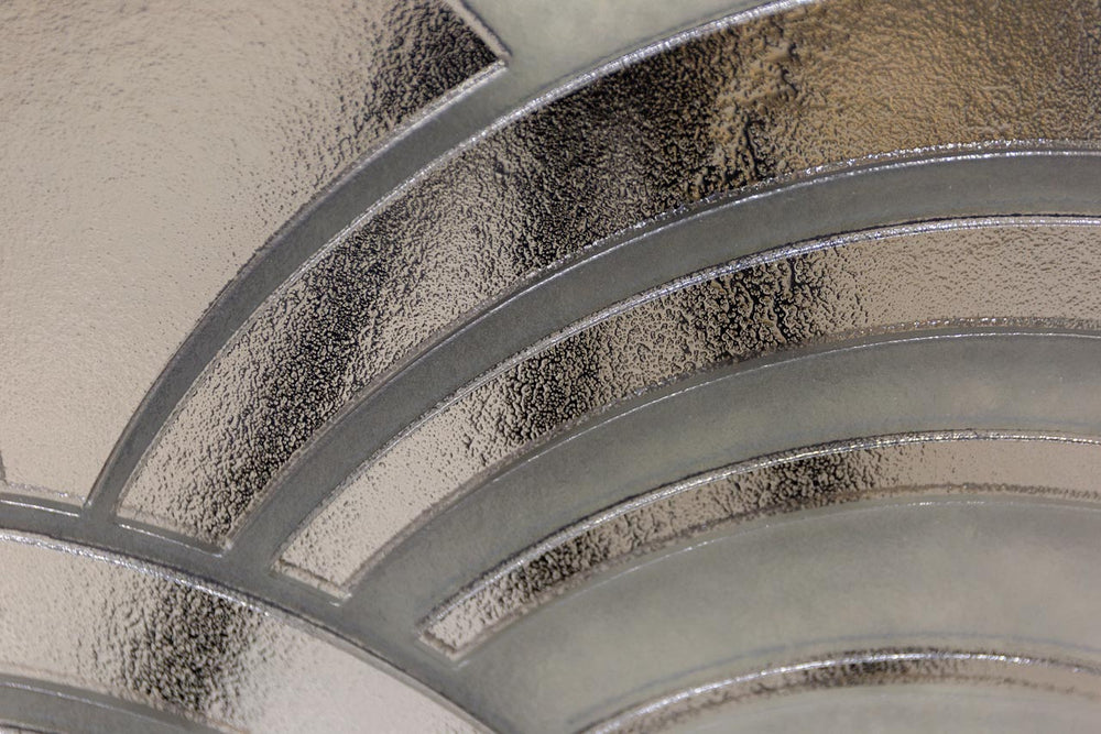 Close-up of the Mermaid glass wall panel featuring an intricate metallic wave pattern with reflective silver and frosted glass elements.