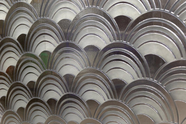 Close-up of the Mermaid glass wall panel featuring an intricate metallic wave pattern with reflective silver and frosted glass elements.