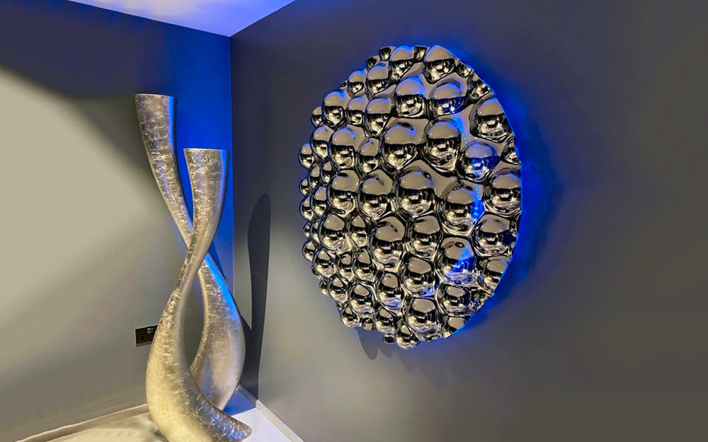 A modern 3D bubbles wall sculpture with reflective mirror spheres, enhanced by ambient blue backlighting. 