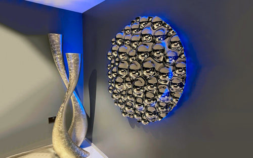 A modern 3D bubbles wall sculpture with reflective mirror spheres, enhanced by ambient blue backlighting. 