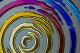 Contemporary 3D glass wall art with a dynamic circular design, blending gold, blue, and violet hues.