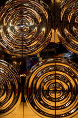 Close-up of reflective golden glass wall panels 'X4' with circular patterns with a dynamic light and depth effect.