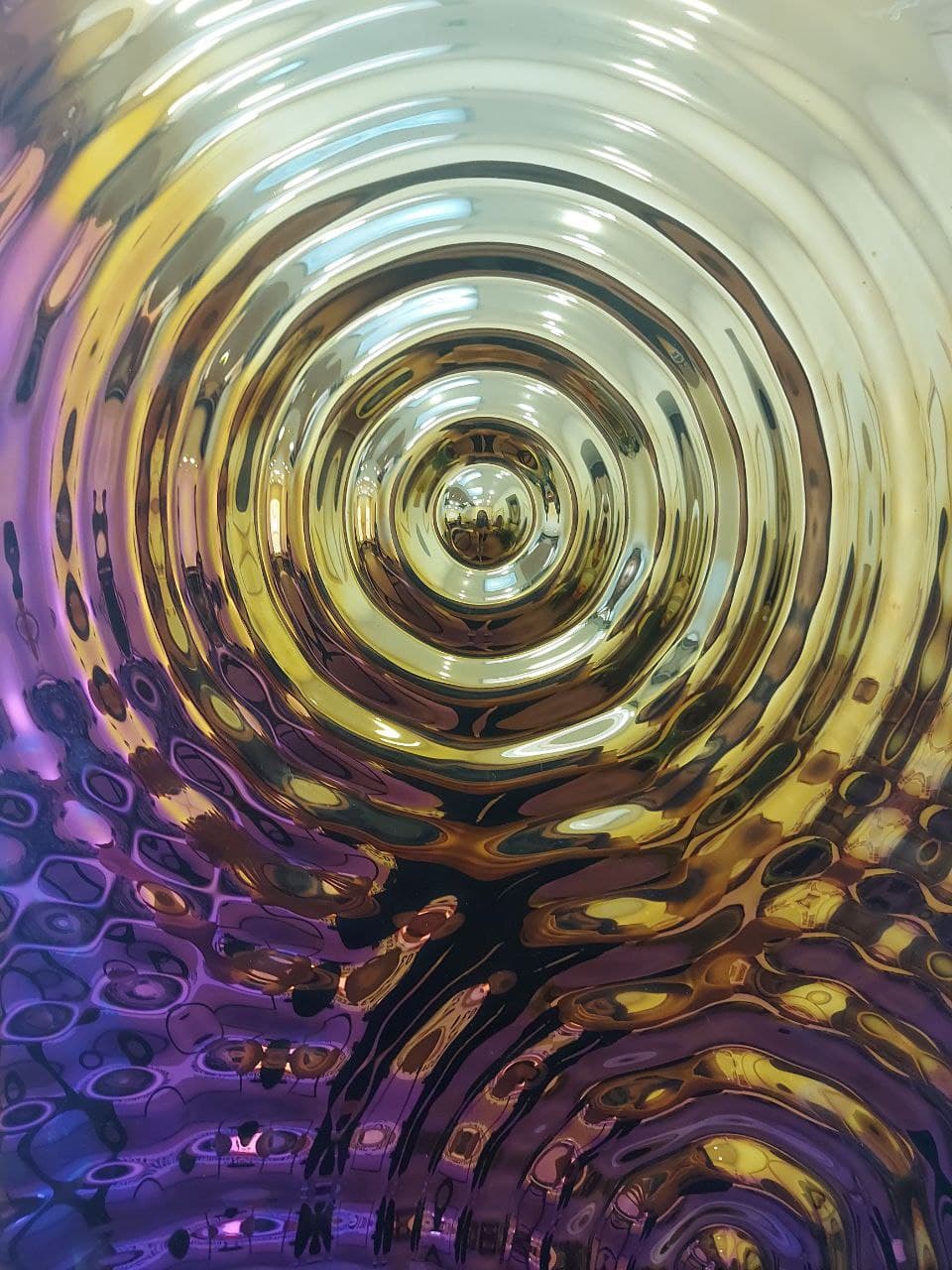 Interference 5 Drops Mural, a modern glass wall art piece with a dynamic ripple pattern in vibrant gold, purple, and blue hues.