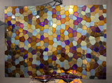 A full view of a polygonal mosaic glass wall panel with a blend of iridescent, bronze, and gold tiles. The design elevates any luxury space.
