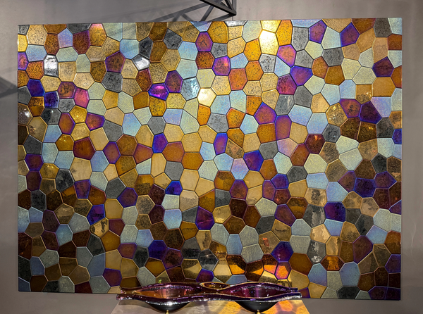 A full view of a polygonal mosaic glass wall panel with a blend of iridescent, bronze, and gold tiles. The design elevates any luxury space.