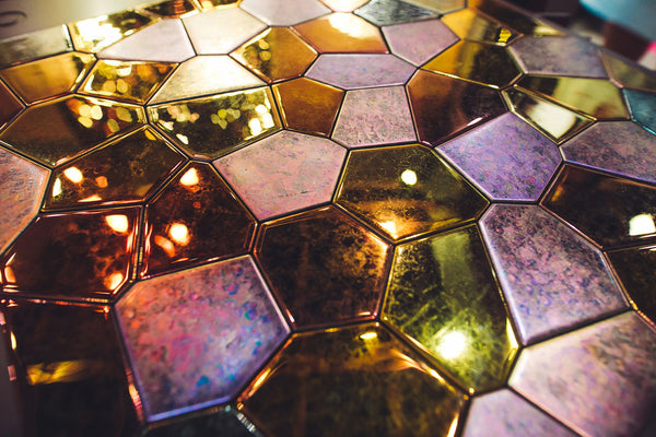 A polygonal glass mosaic panel with a reflective surface and rich textures. The interplay of colors and materials creates a unique visual effect.