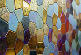 A detailed view of a polygonal mosaic glass wall panel. The mix of matte and glossy textures produces a sophisticated and artistic look.