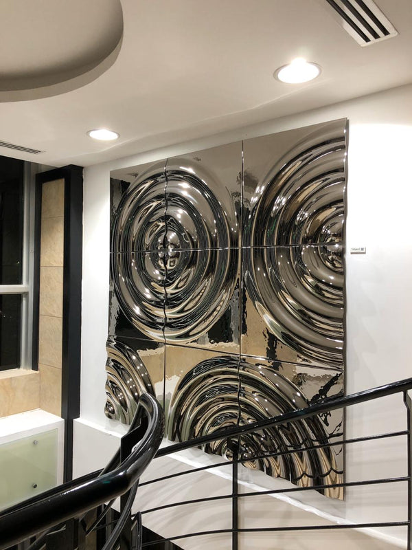 Reflective modular silver glass wall panels  with circular patterns in a modern interior near a staircase with black railing