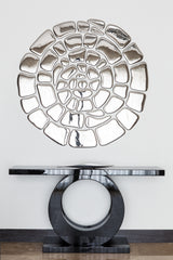 Spiral mirror wall art above a modern black console table. Reflective glass elements arranged in an artistic spiral design for a sophisticated entryway.