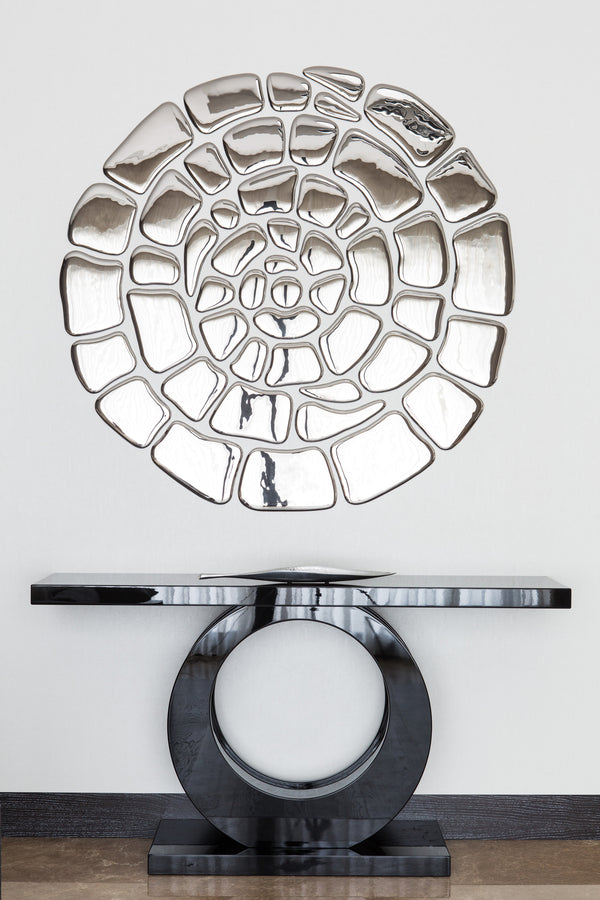 Spiral mirror wall art above a modern black console table. Reflective glass elements arranged in an artistic spiral design for a sophisticated entryway.