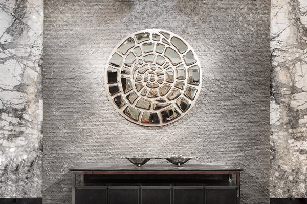 Elegant spiral mirror wall art mounted on a textured luxury interior wall.