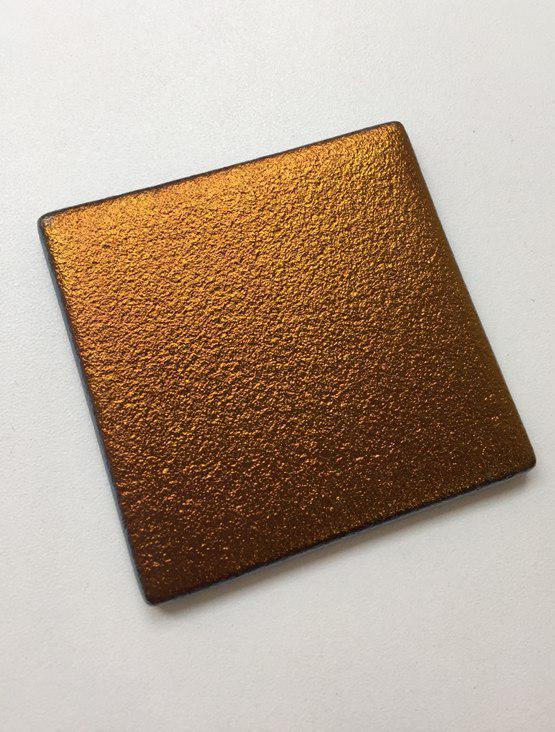 A single glass tile from the Tetris wall panel collection features a rich brond texture and a metallic structured finish.