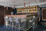 The Vento Silver glass wall panel integrated into a bar counter, featuring a backlit luxury textured glass surface.