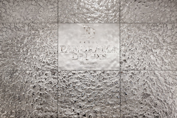  The Vento Silver glass wall panel installed in the Panorama De Luxe hotel, featuring an engraved logo on a mirrored textured surface.