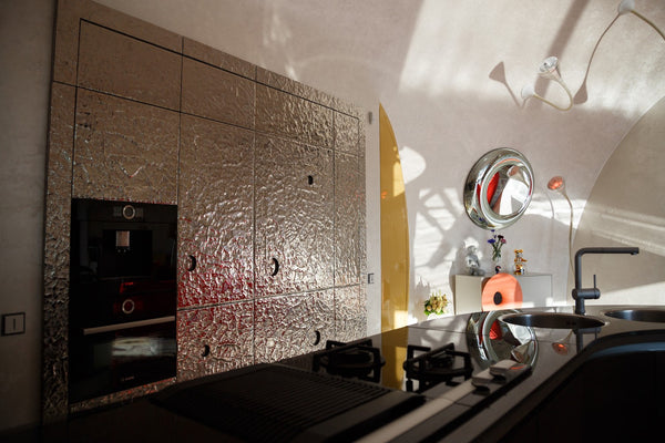 A contemporary kitchen design featuring Vento Silver wall panels, adding a reflective and modern aesthetic to the cabinetry.