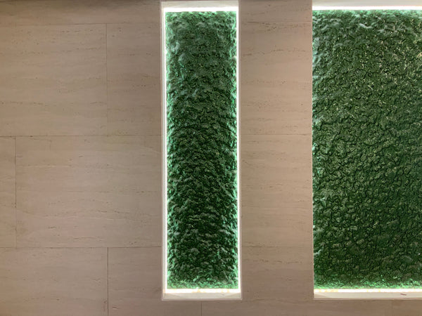 Vertical illuminated Green Planet glass panels integrated into a modern wall design.