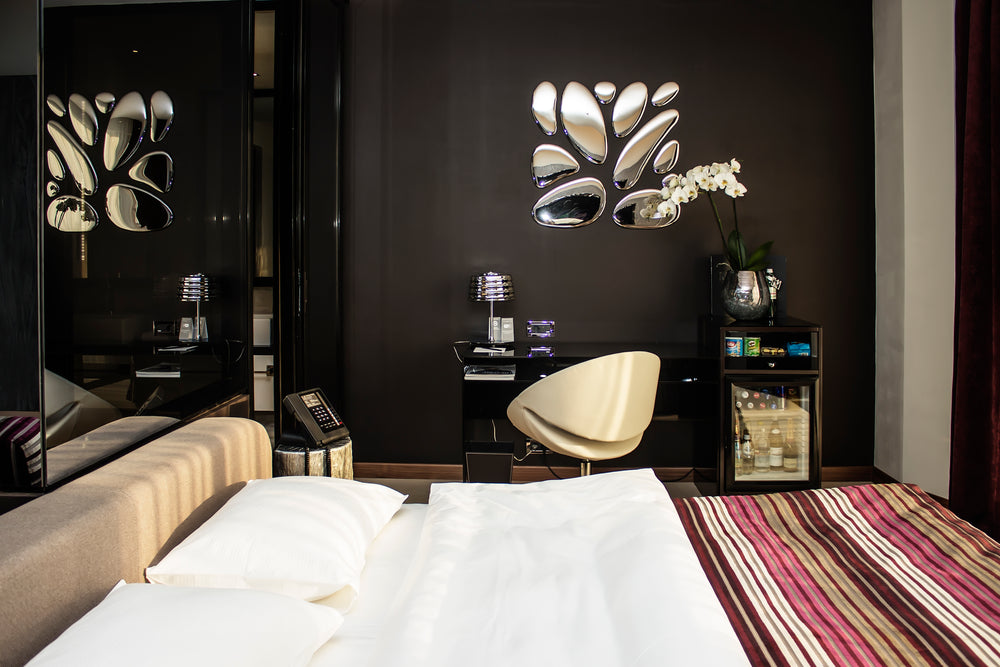 Modern wall decor installation featuring 11 irregularly shaped silver-finished drops mounted on a dark wall above a sleek desk with a modern chair.